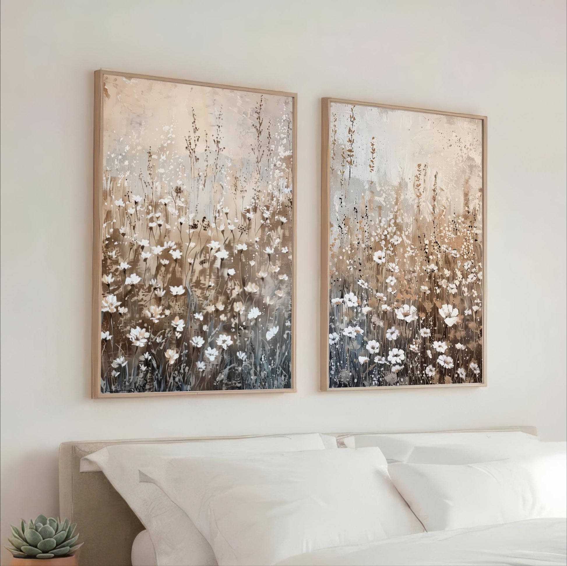 two large paintings of flowers hanging on a wall above a bed with white pillows.