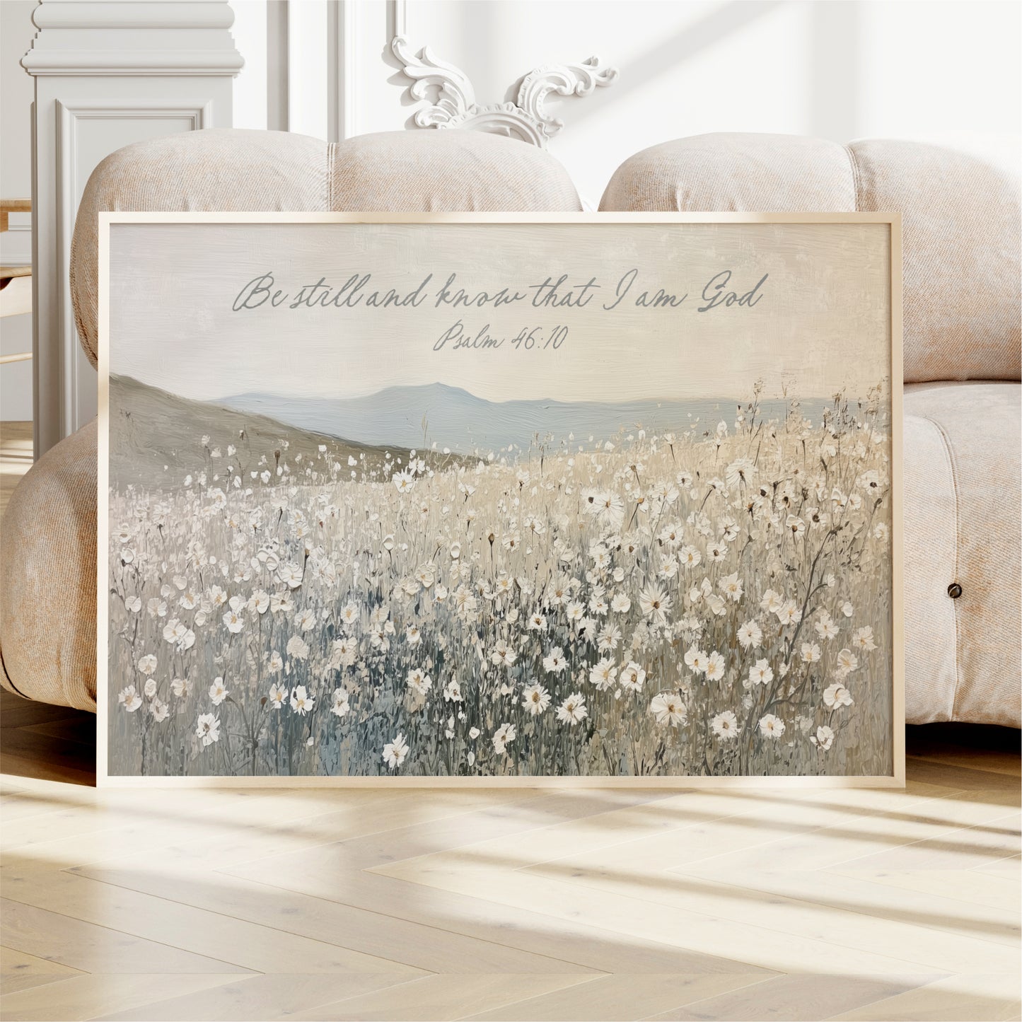 A framed painting of a field of flowers is displayed on a white couch in a room.