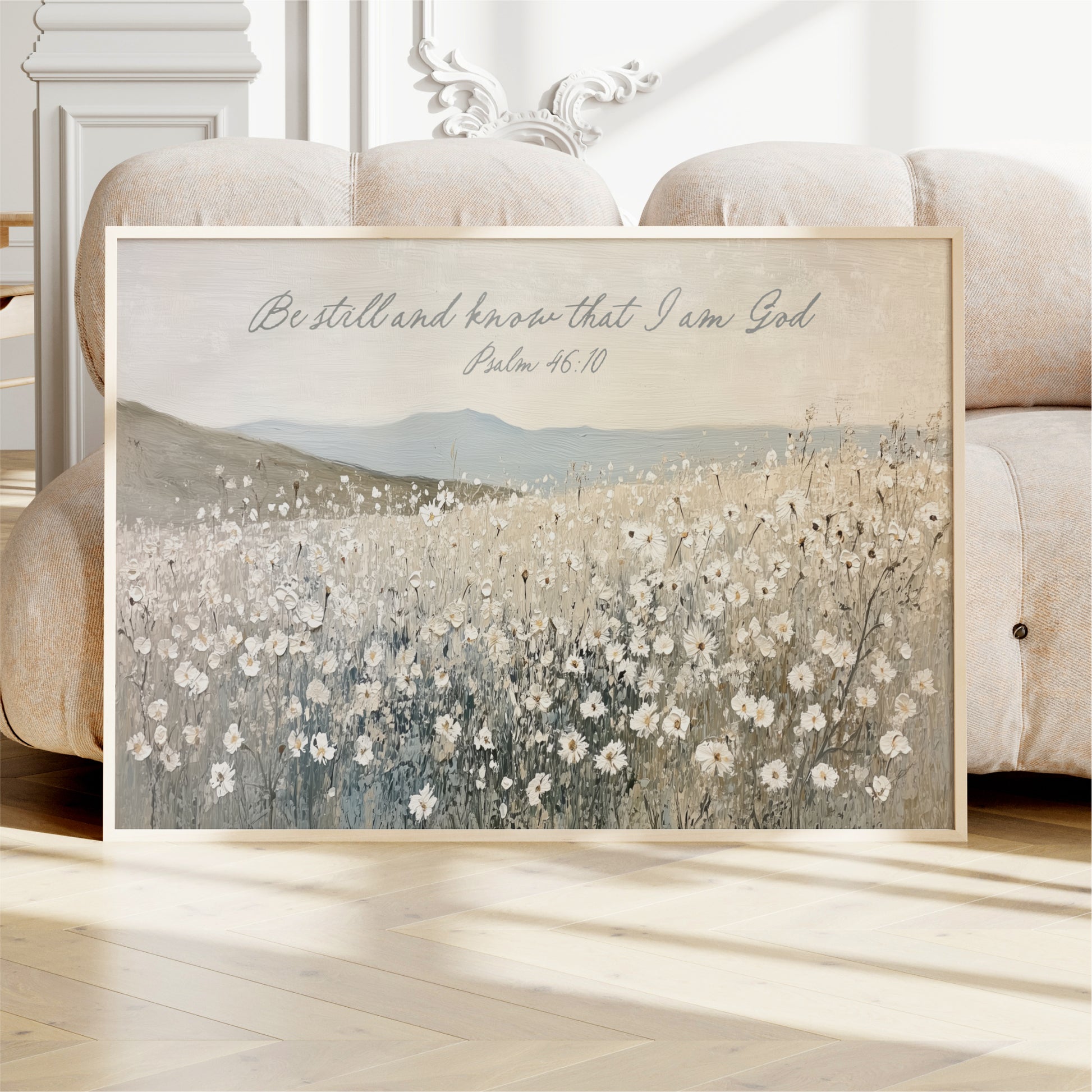 A framed painting of a field of flowers is displayed on a white couch in a room.