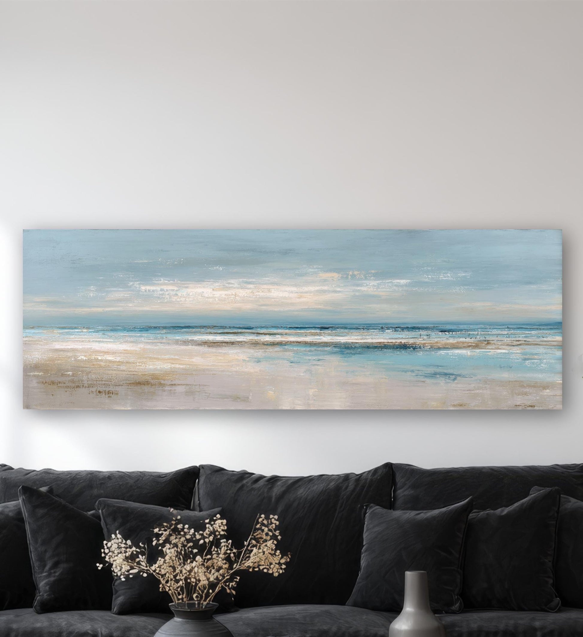 a large landscape painting hanging on a wall above a black couch with decorative pillows.