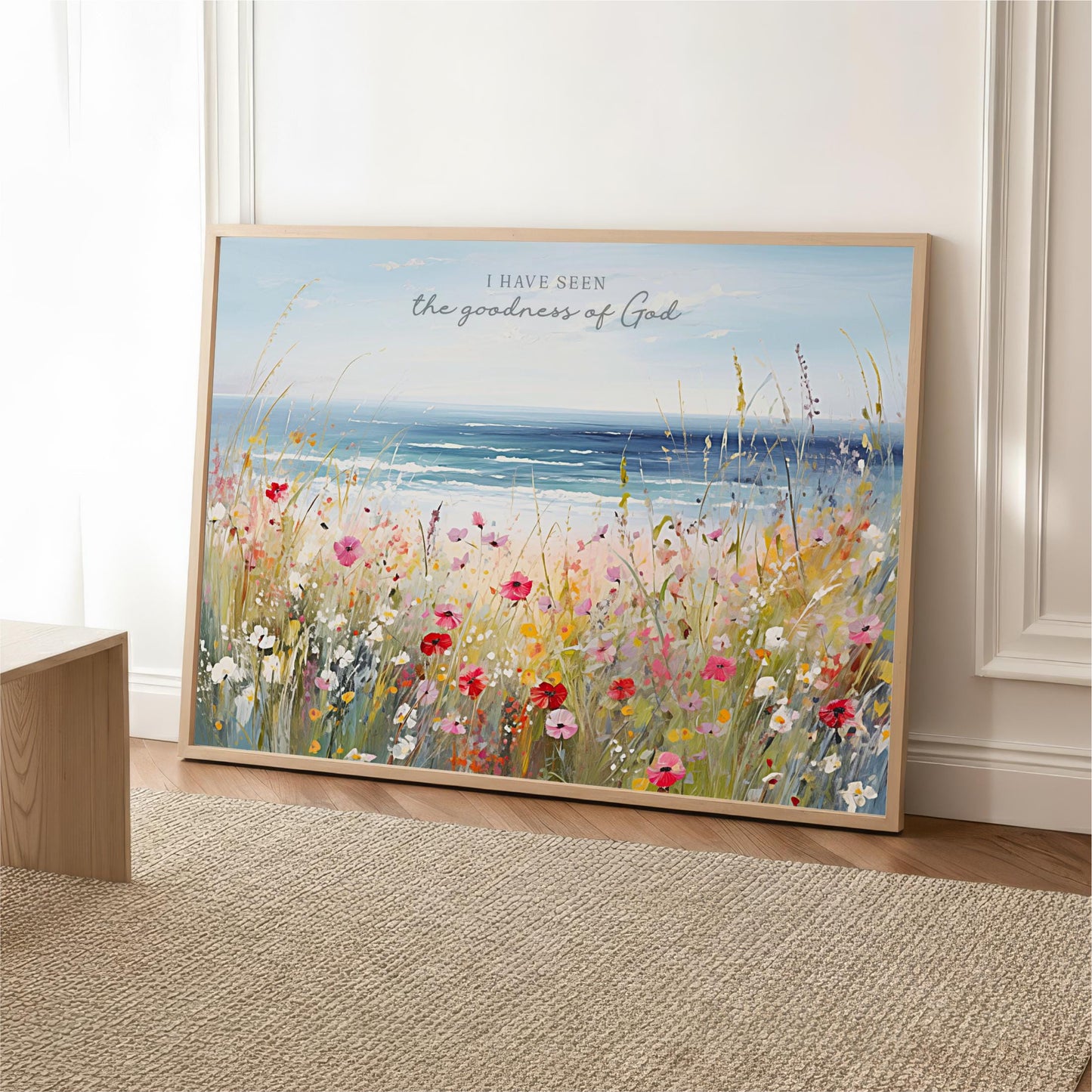 A framed painting depicting a vibrant field of flowers with a serene body of water in the background, accompanied by the text "I HAVE SEEN the goodness of GOD".