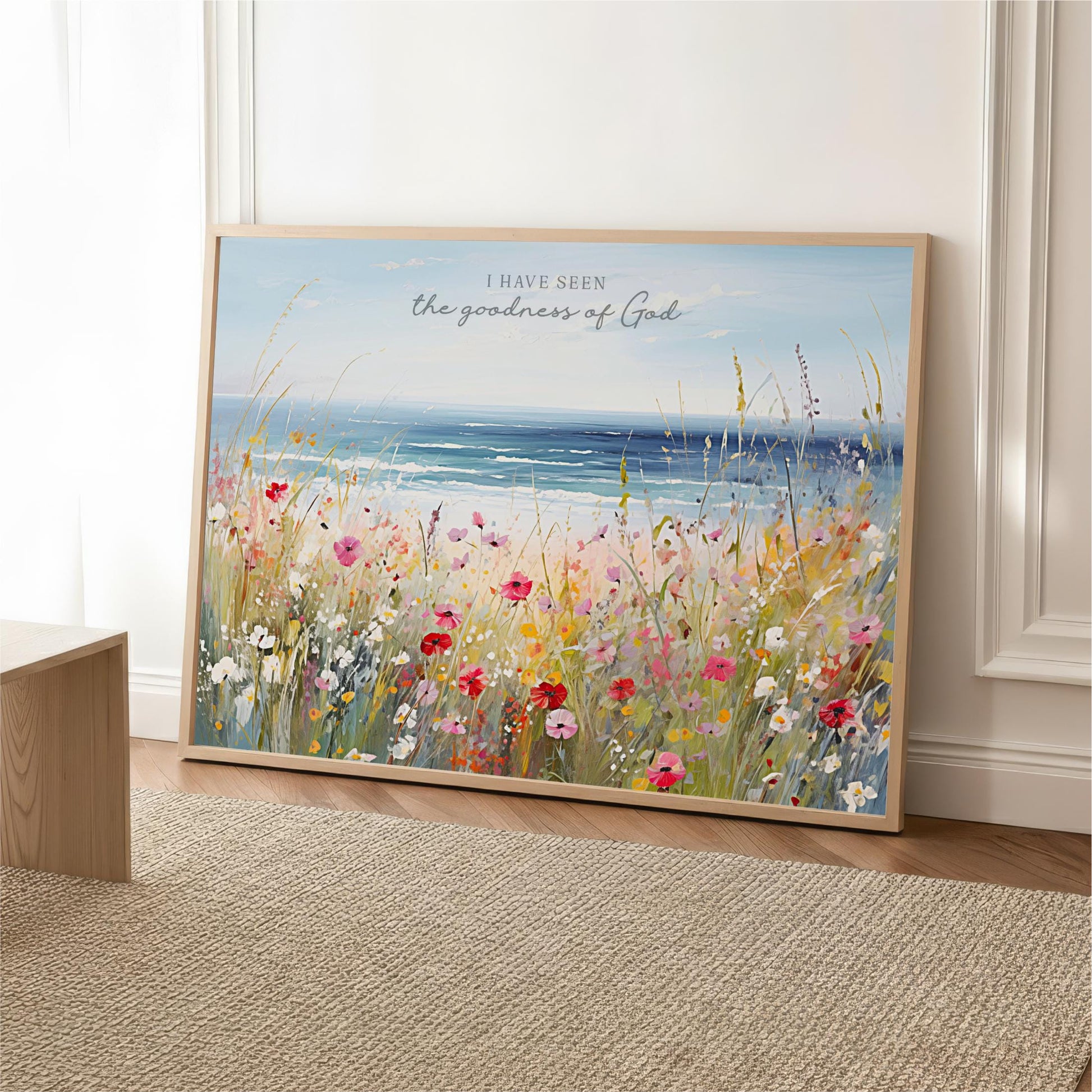 A framed painting depicting a vibrant field of flowers with a serene body of water in the background, accompanied by the text "I HAVE SEEN the goodness of GOD".