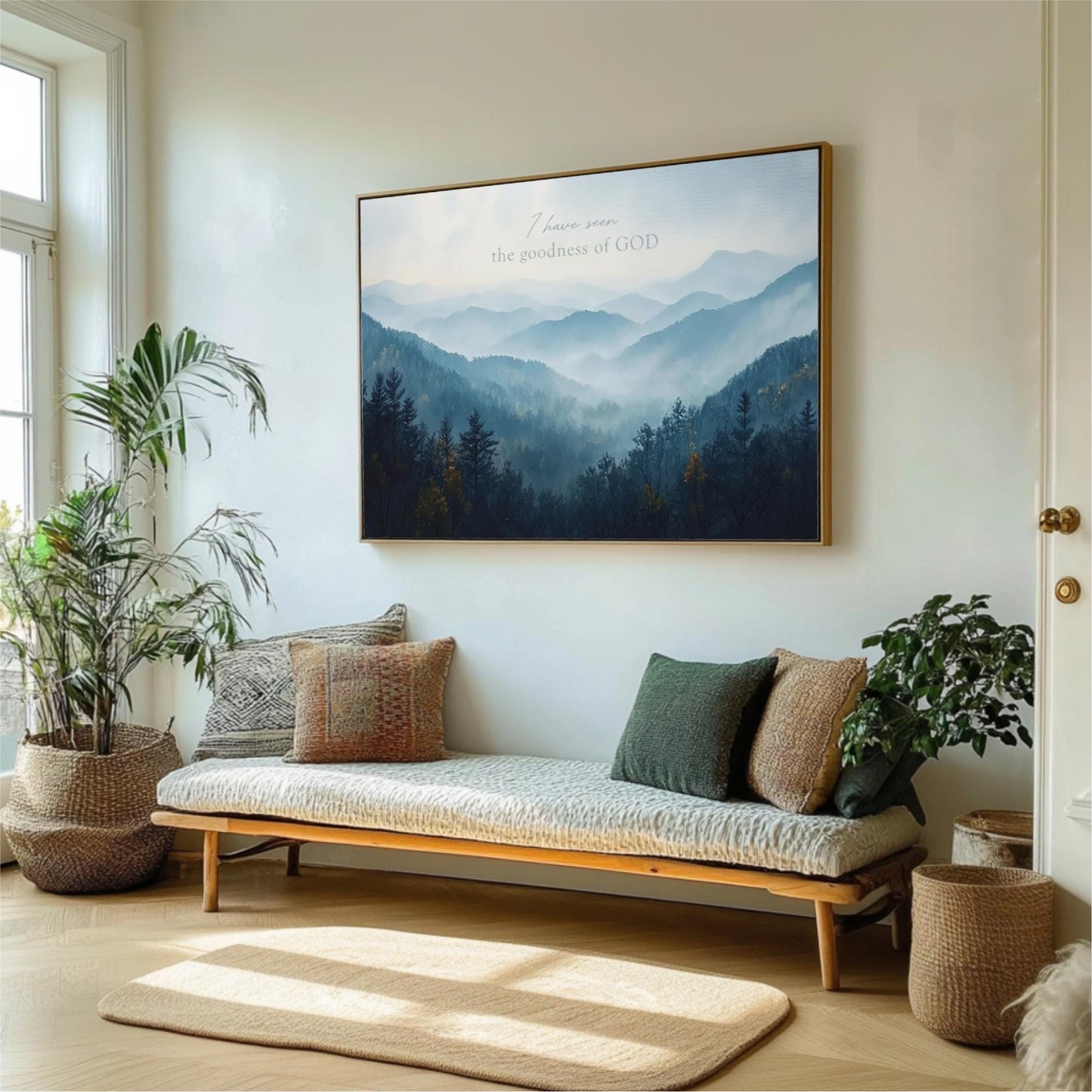a living room with a large framed picture of a mountain landscape hanging on the wall above a couch with pillows. The room is decorated with potted plants and a rug, creating a cozy and inviting atmosphere.