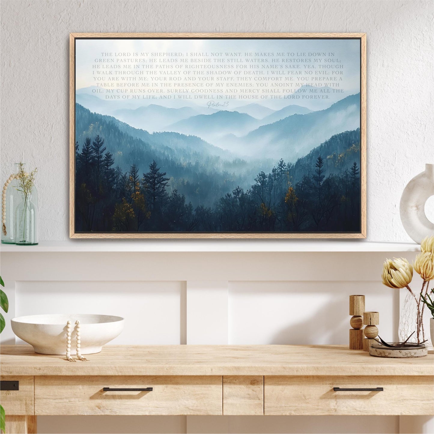 a framed landscape painting depicting a serene mountain scene with trees and a misty, hazy atmosphere.