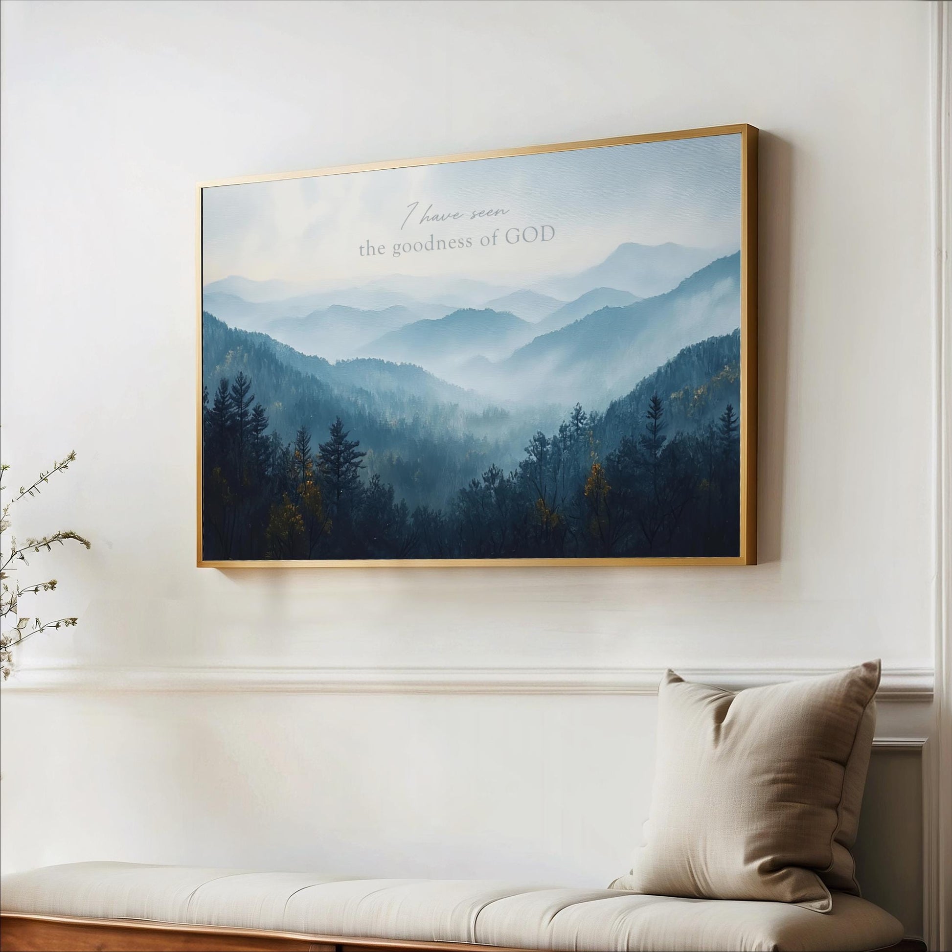 a large framed picture of a mountain landscape with trees and mountains in the background, hanging on a wall above a bench.