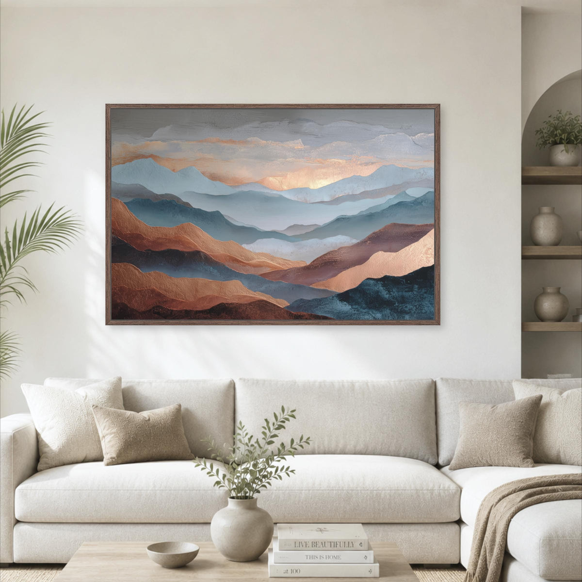 a large, framed painting of mountains hanging on a wall above a white sofa in a living room.