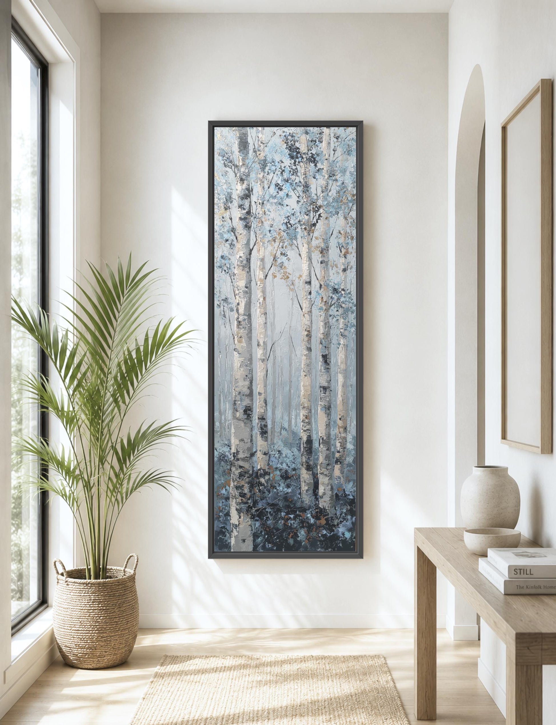 a large painting of a forest scene hanging on a wall, with a large window allowing natural light to illuminate the space.