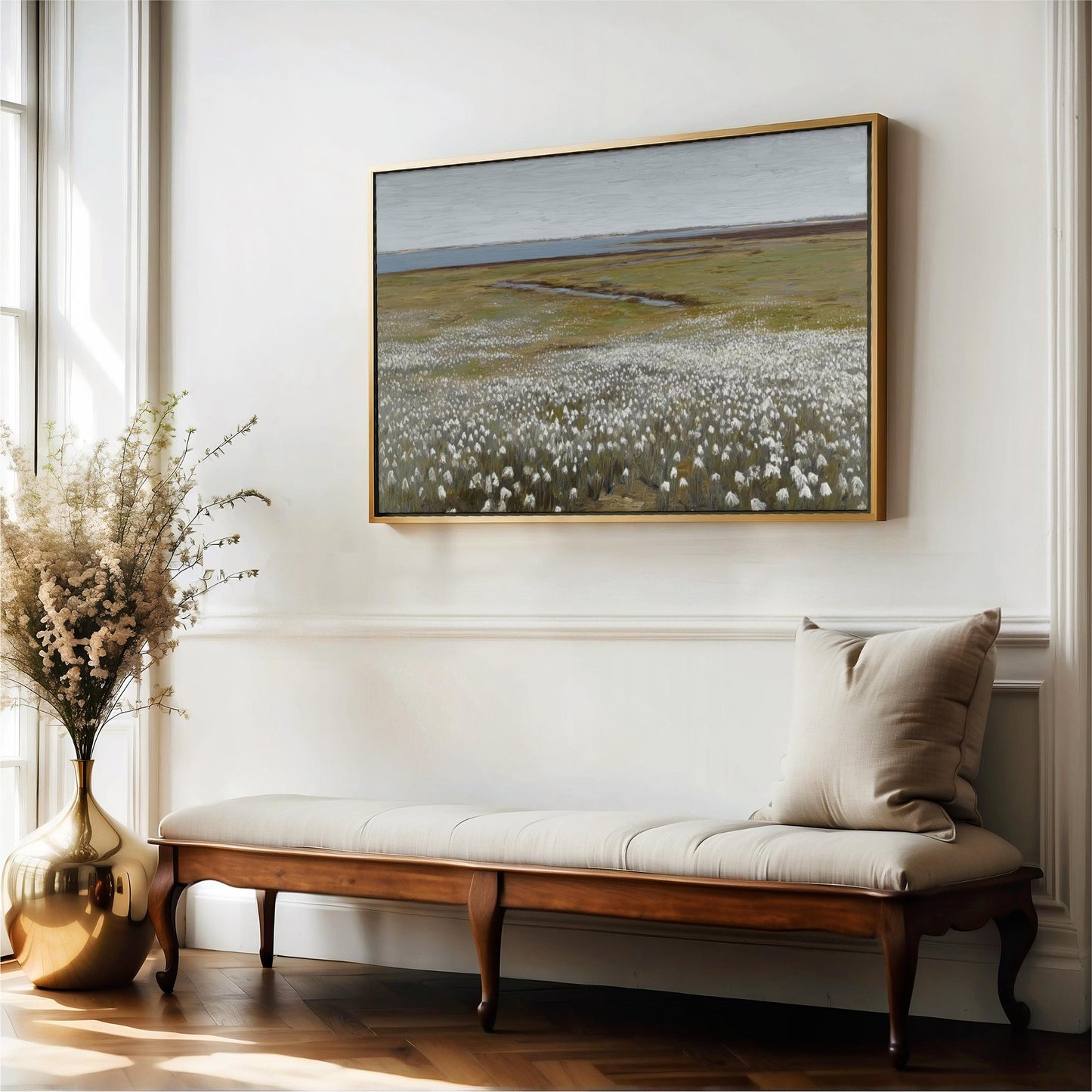 a large painting of a field with white flowers hanging on a white wall above a wooden bench with a beige cushion.