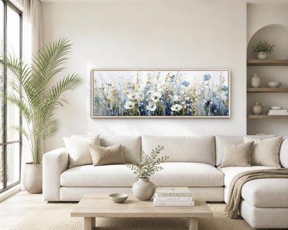 a cozy living room with a large white sofa, a wooden coffee table, and a framed painting of a field of flowers hanging on the wall.