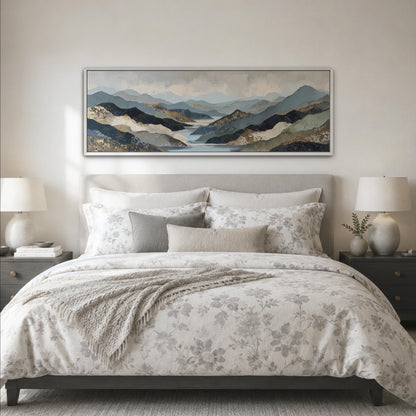 a large bed with a floral bedspread and pillows, flanked by two nightstands with lamps. Above the bed is a large framed landscape painting depicting a mountainous, forested scene.
