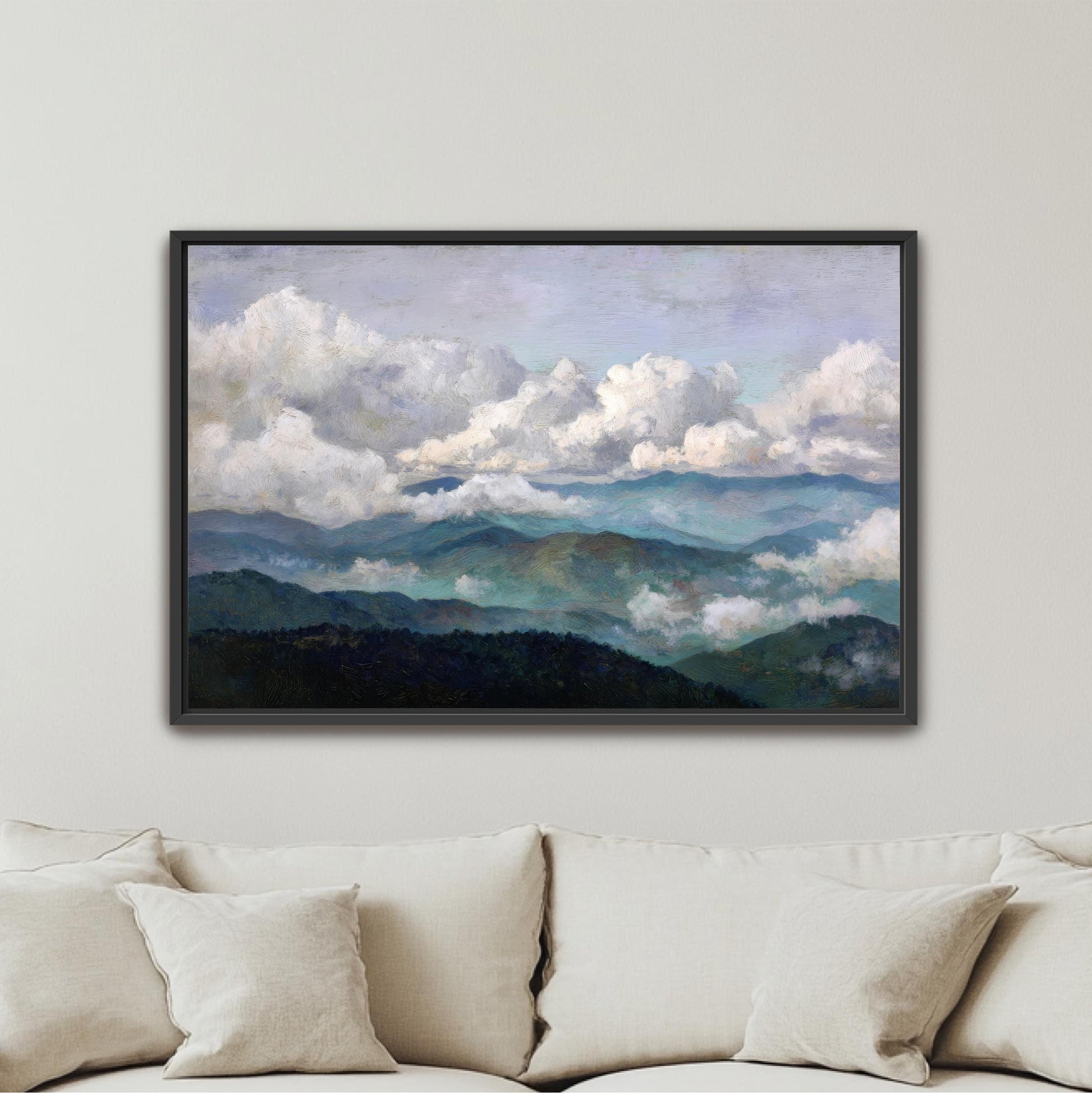 The image is a framed painting of a mountainous landscape with clouds, hanging on a wall above a couch.