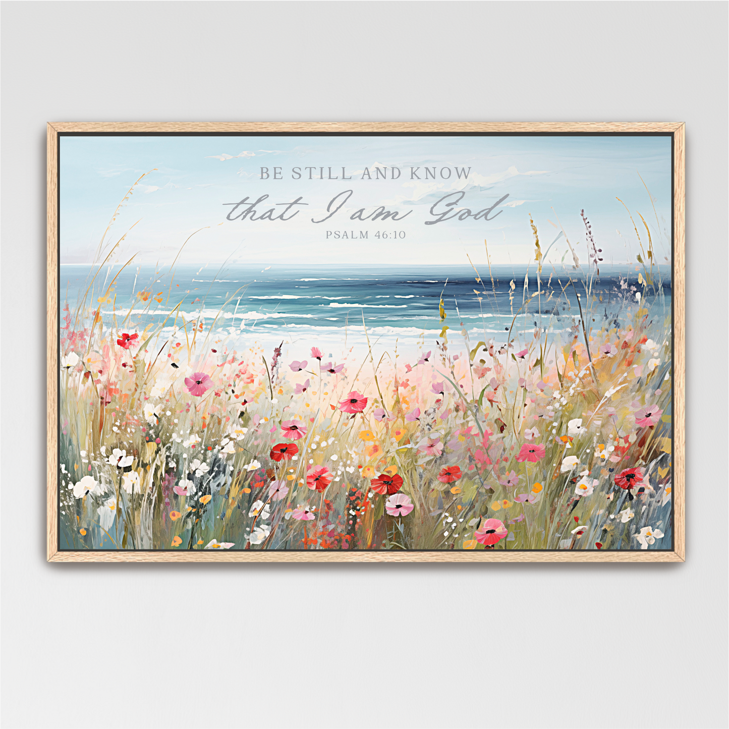The image is a framed painting depicting a serene landscape with a field of colorful flowers in the foreground and a body of water in the background. The text overlay reads "Be Still and Know that I am God" from Psalm 46:10.
