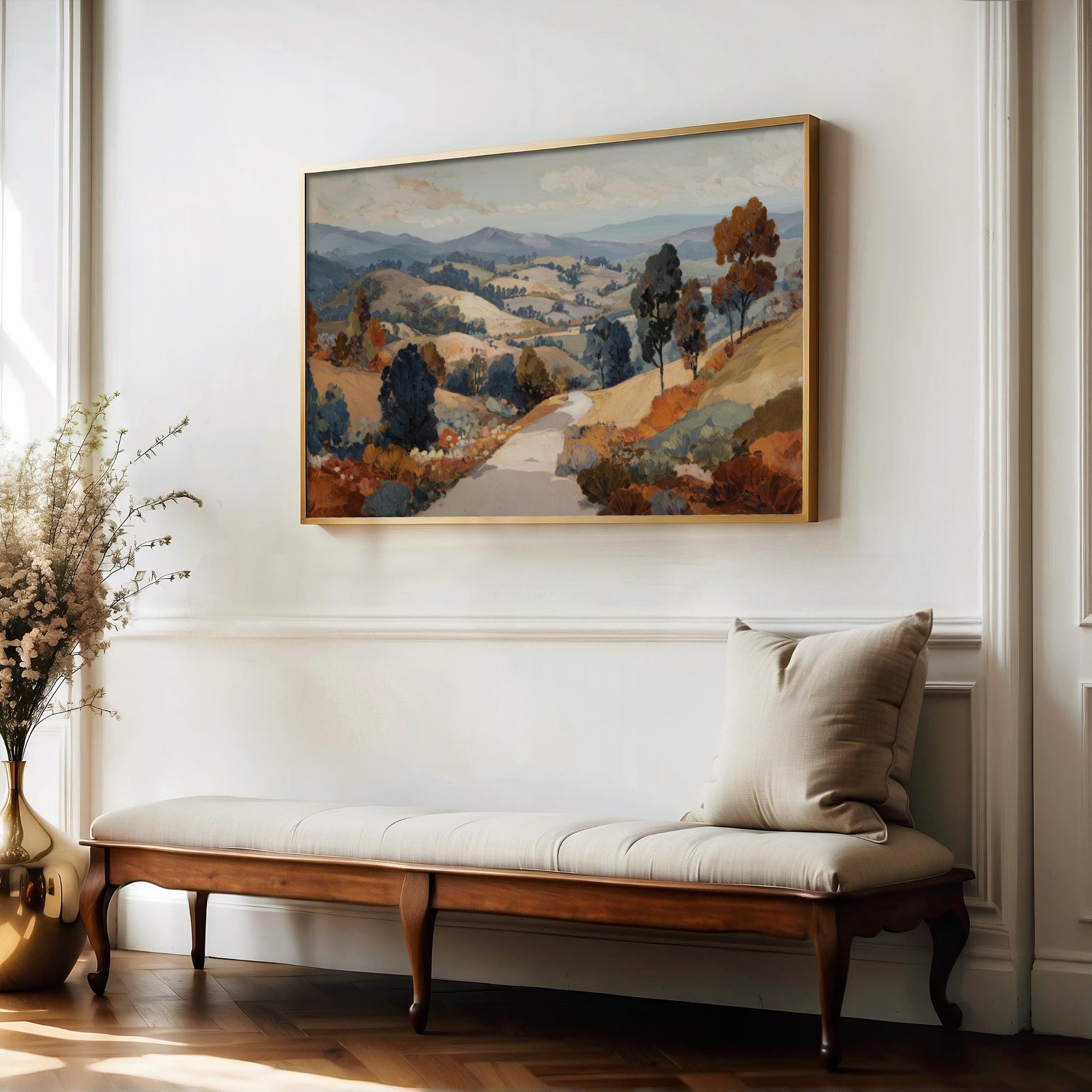 a large landscape painting hanging on a white wall above a wooden bench with a white cushion.