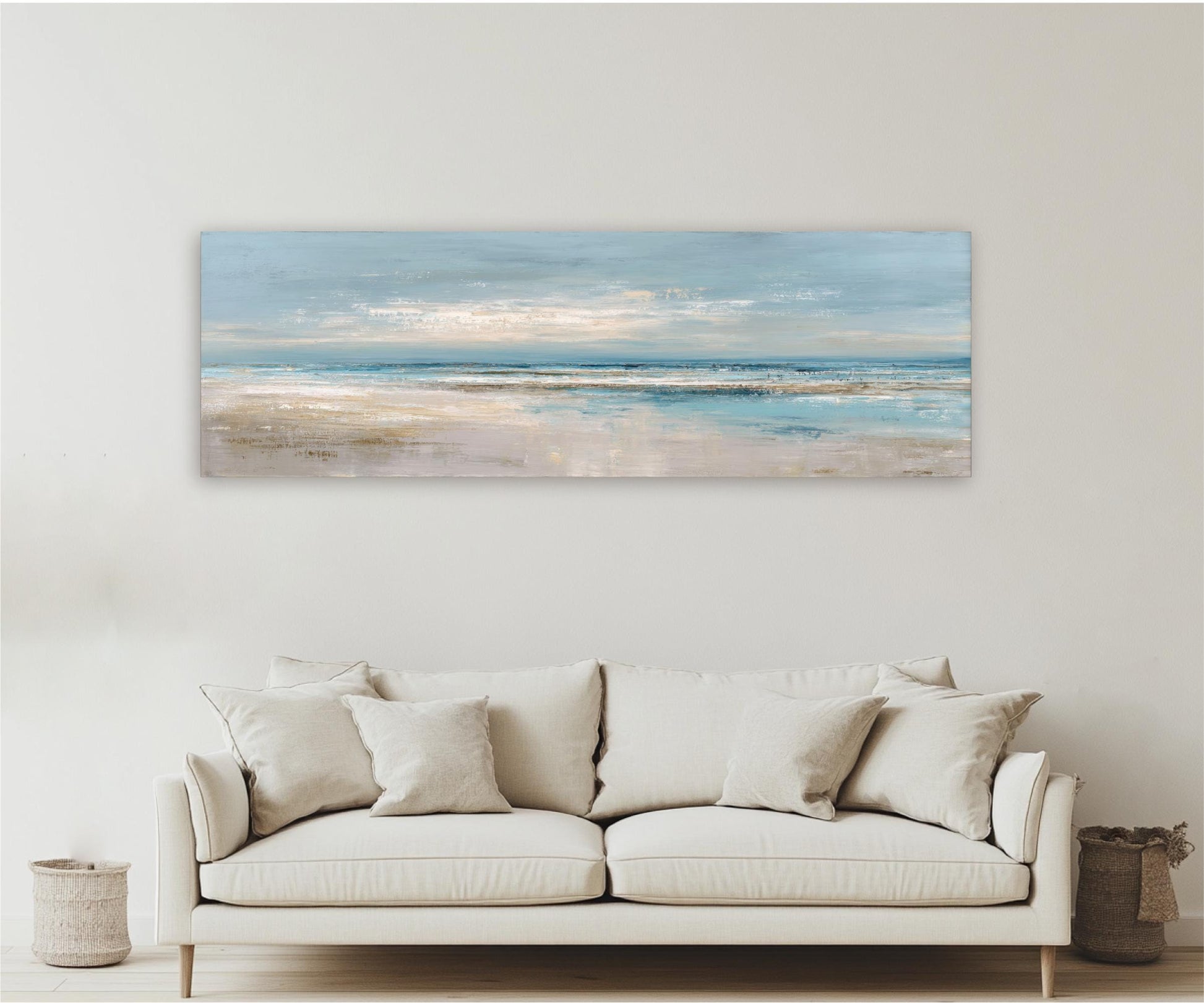 a large, rectangular painting of a beach scene hanging on a wall above a beige sofa with white pillows.