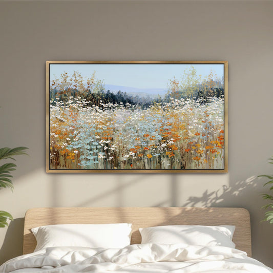 a large, framed painting of a field of flowers hanging above a bed with white pillows.