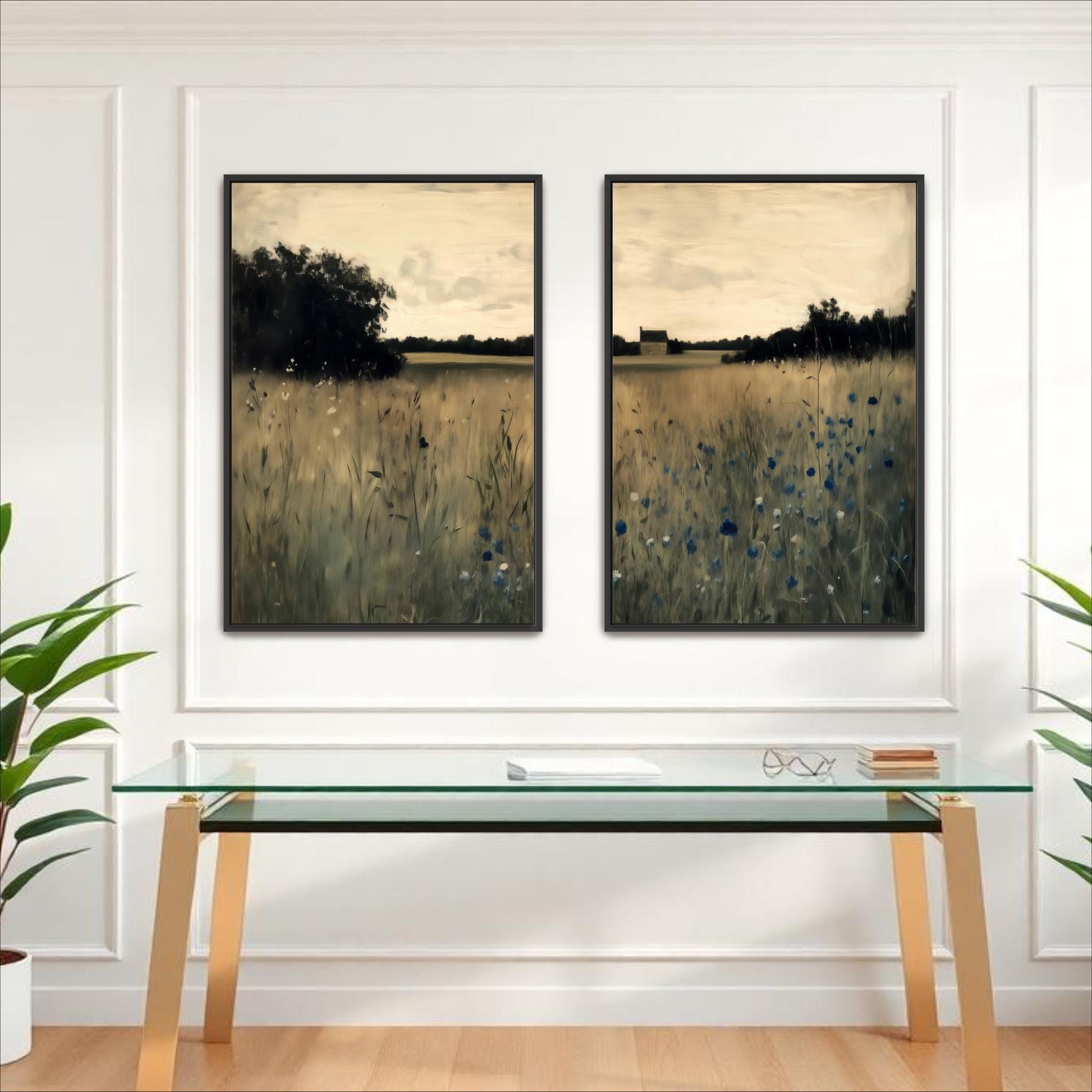 two framed paintings of a field with tall grass and trees, hanging on a white wall above a glass desk with a computer monitor and other office supplies.