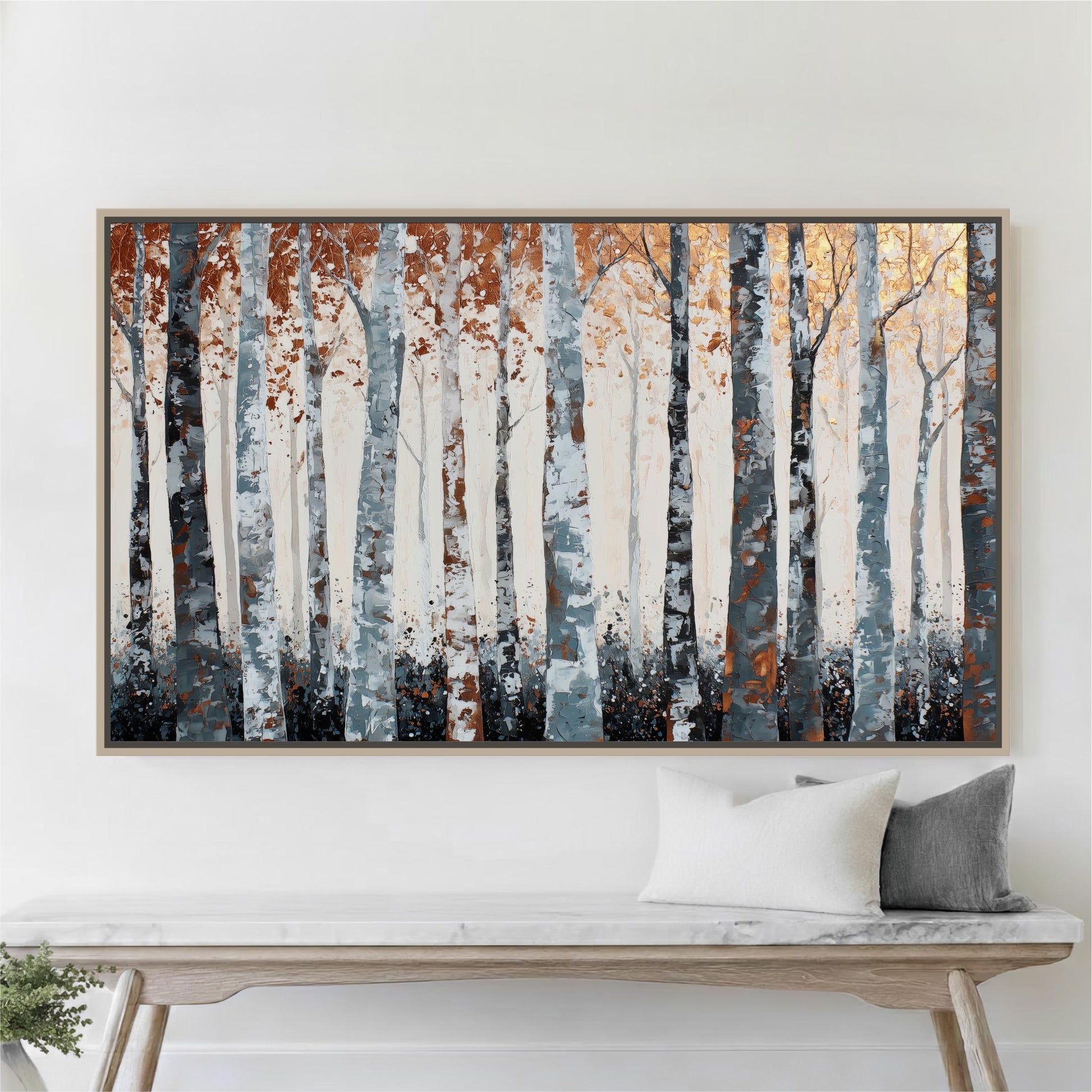 a large painting of a forest with tall trees in shades of blue, orange, and white. The painting is displayed on a white wall above a wooden bench, which has two pillows on it.