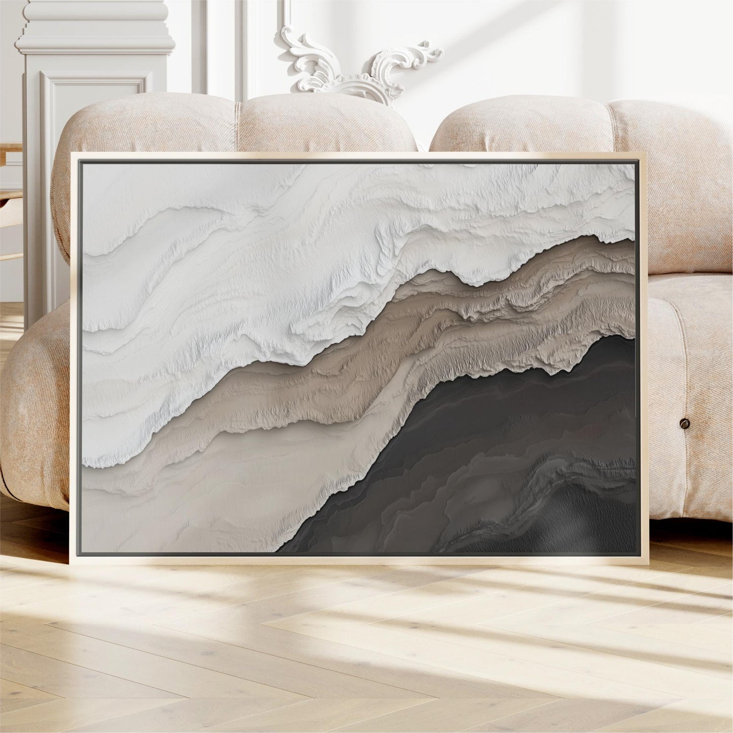a large abstract painting with a mix of white, brown, and black colors, displayed on a wooden floor in front of a couch.