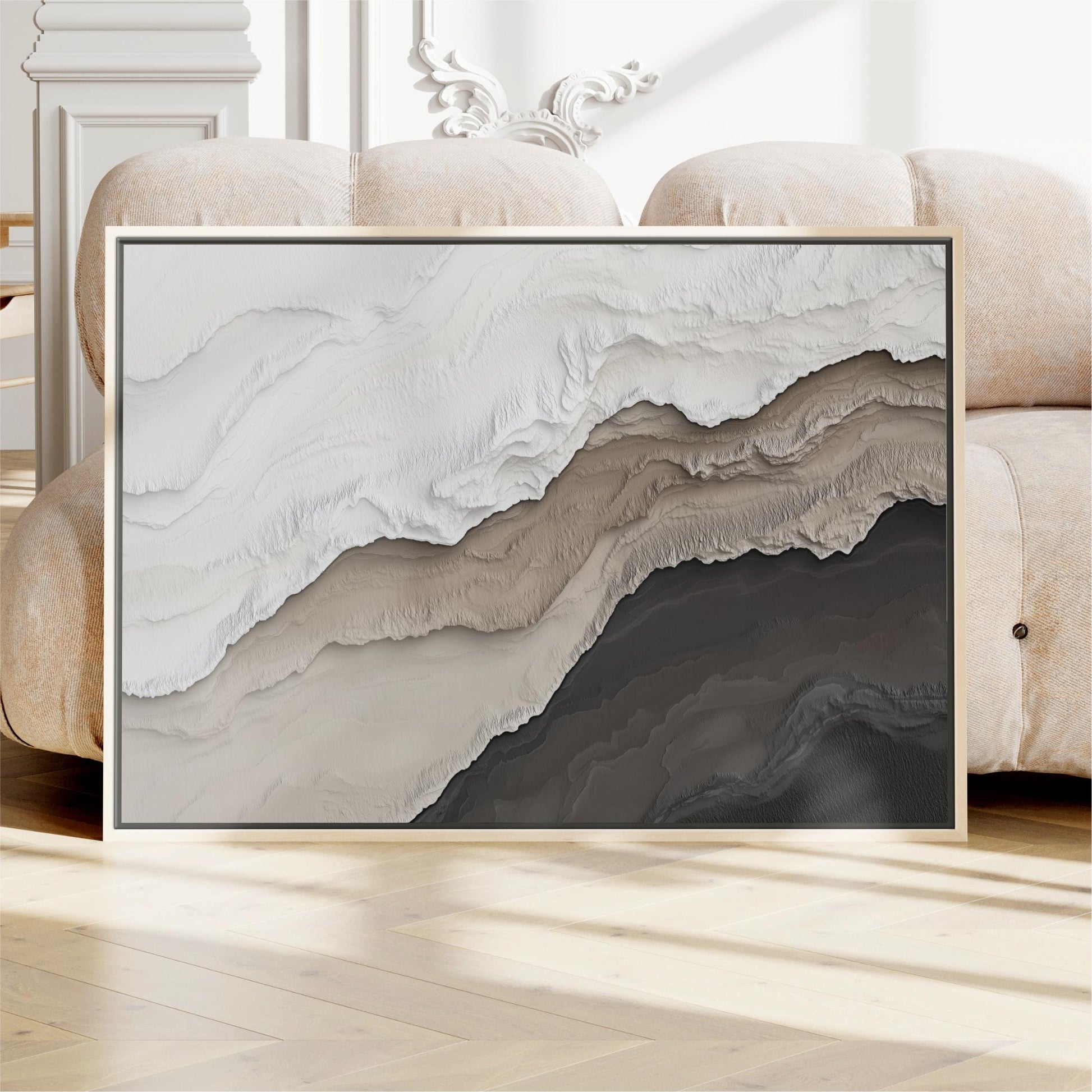 a large abstract painting with a mix of white, brown, and black colors, displayed on a wooden floor in front of a couch.