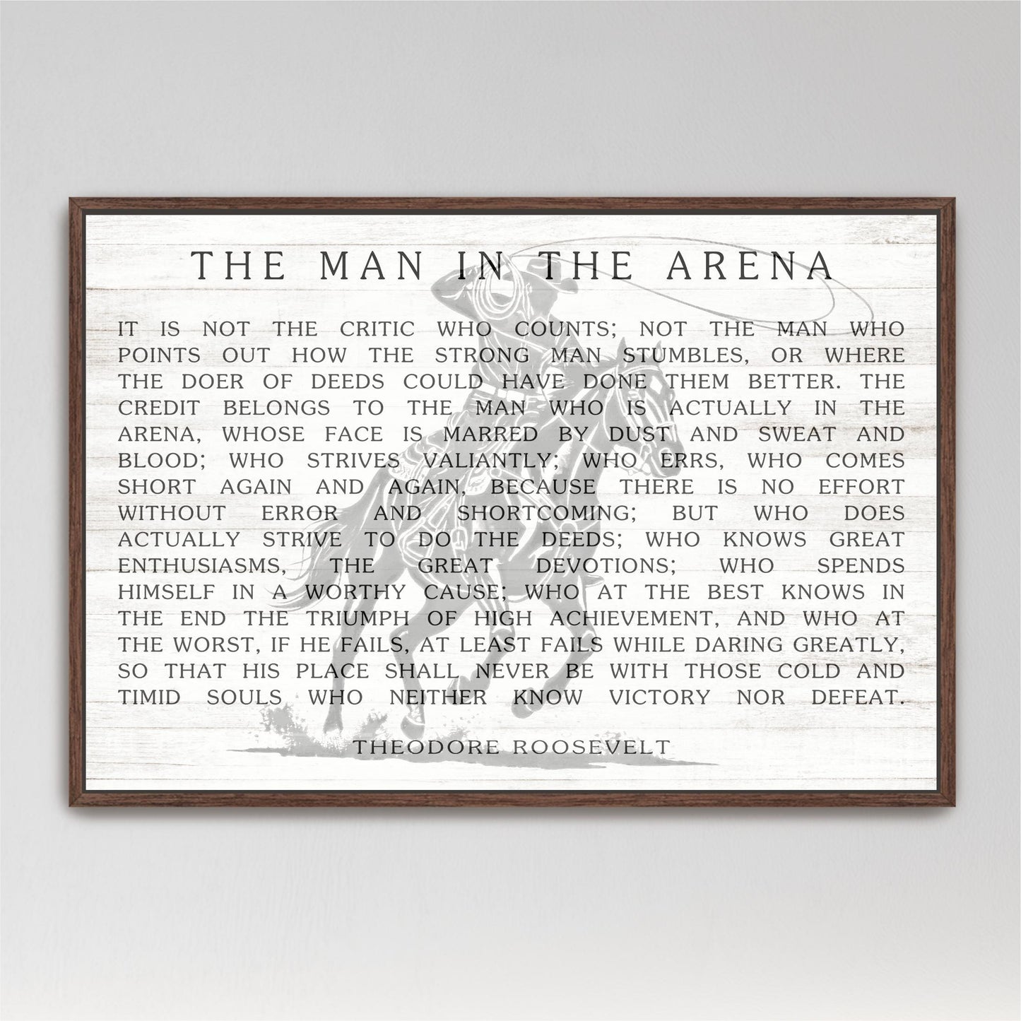 a quote by Theodore Roosevelt, a famous American president, which is framed and displayed in a wooden frame.