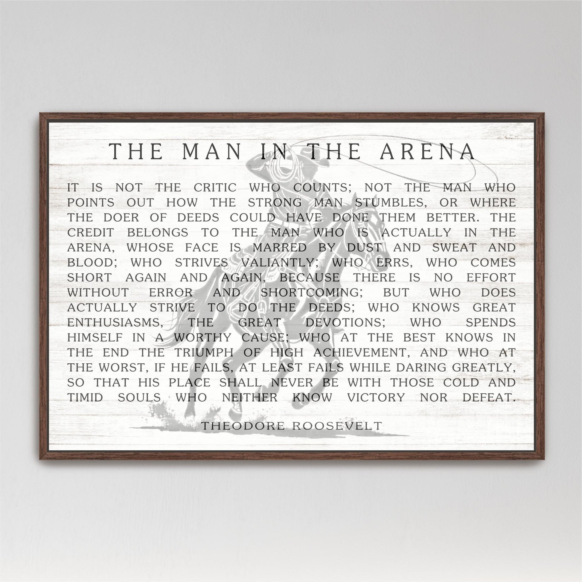 a quote by Theodore Roosevelt, a famous American president, which is framed and displayed in a wooden frame.
