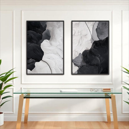 two abstract paintings hanging on a white wall above a glass table.