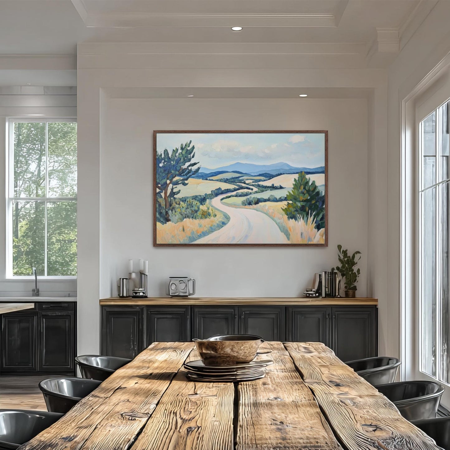 a large painting of a countryside landscape hanging on the wall above a wooden dining table with black chairs.