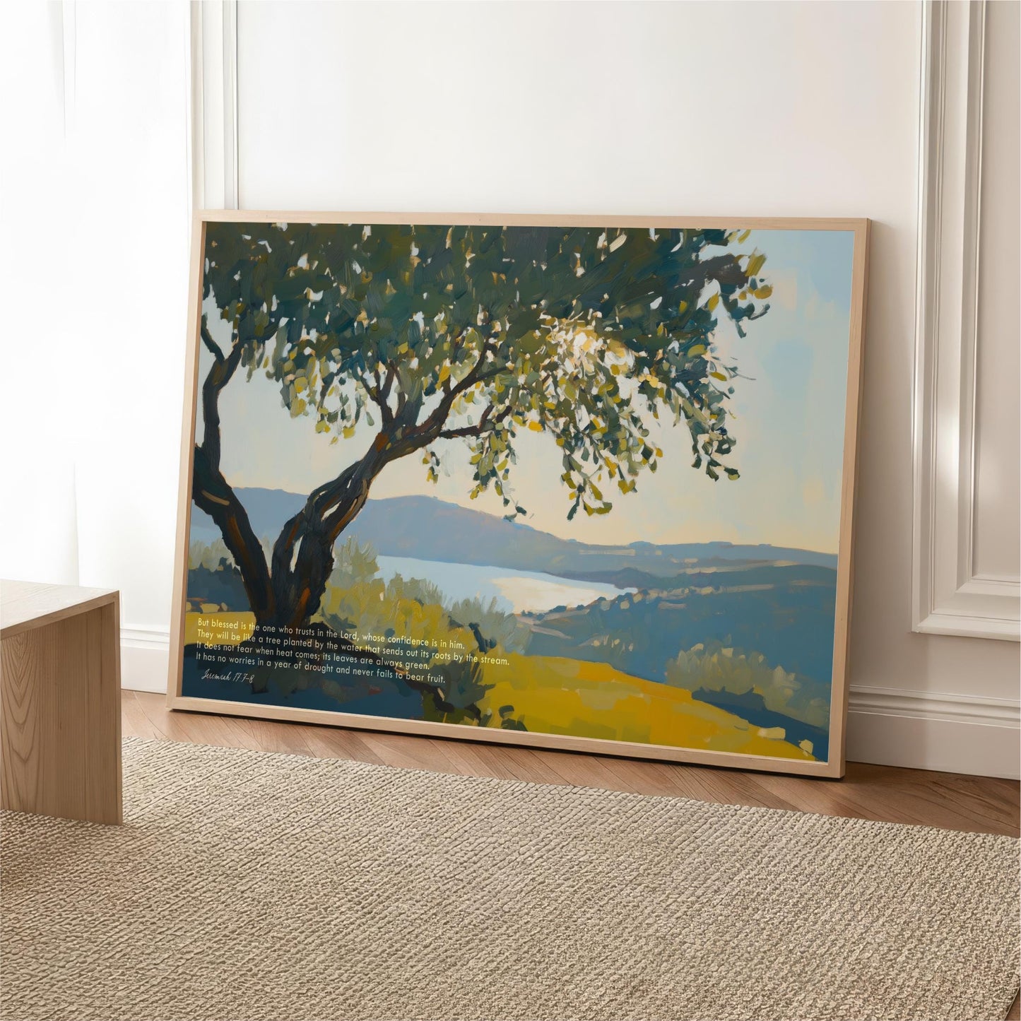 a large painting of a tree with a blue sky and mountains in the background, displayed on a wooden frame on a rug.
