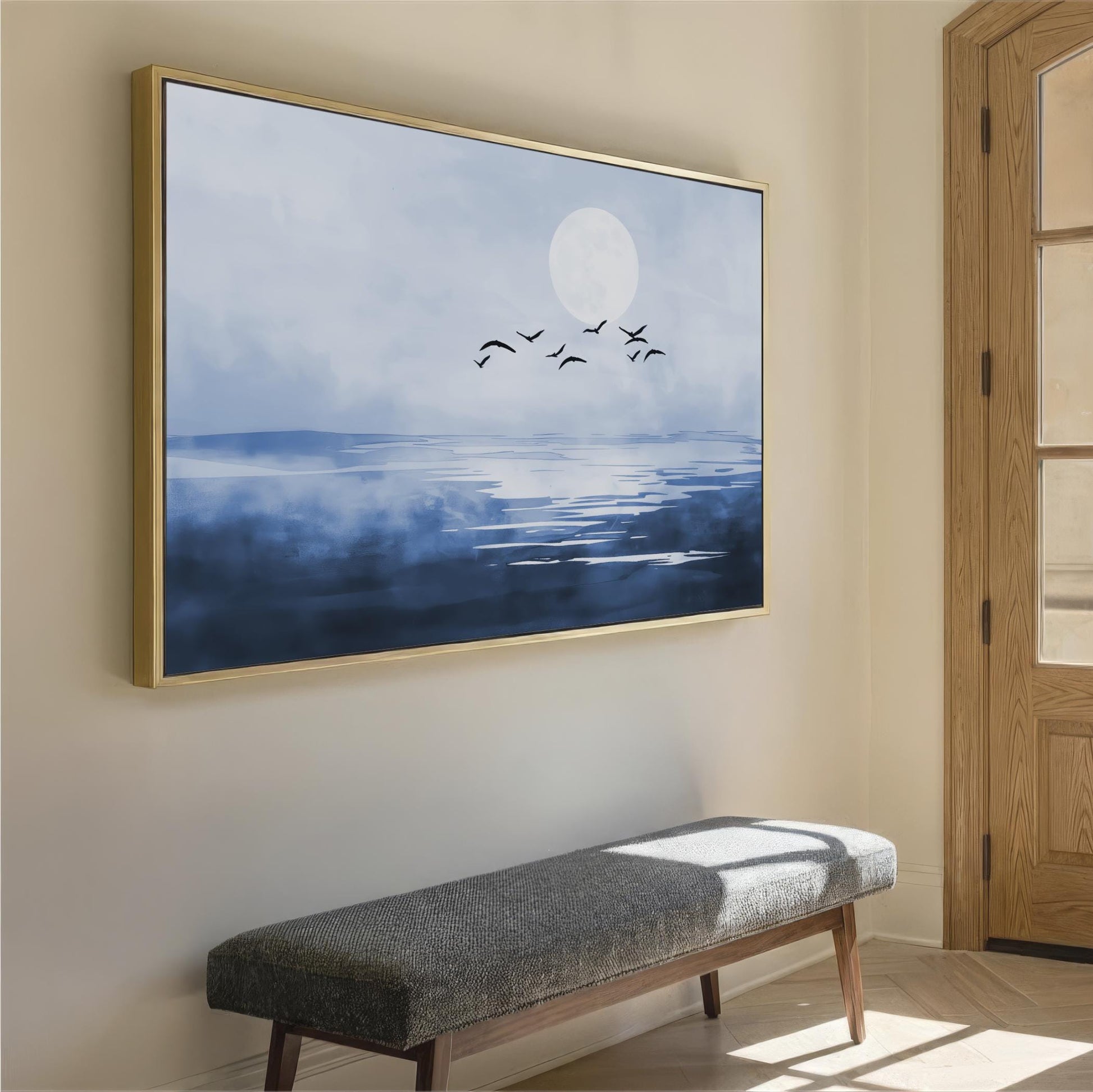 a large framed painting of a serene landscape with a full moon, birds flying in the sky, and a body of water reflecting the moon. The painting is hung on a wall above a gray bench, creating a peaceful and calming atmosphere in the room.