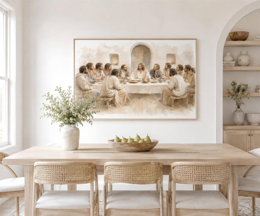 a dining room with a large painting of Jesus Christ and his twelve apostles around a table, with the figures seated and engaged in conversation. The painting is hung on a white wall above a wooden dining table, which is surrounded by woven chairs. A vase of flowers and a bowl of fruit are placed on the table, adding a touch of natural beauty to the scene.