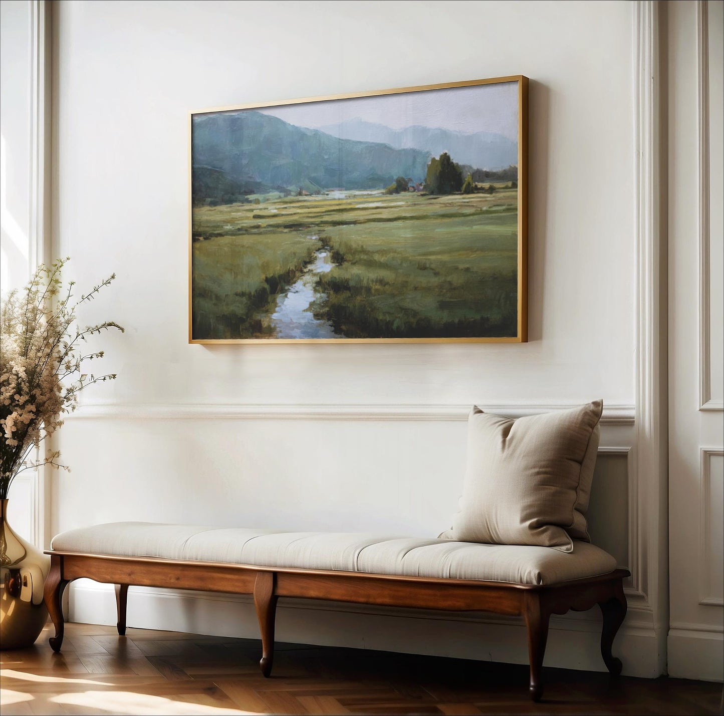 a large landscape painting hanging on a white wall above a wooden bench with a beige cushion.