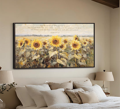 The image is a large painting of a field of sunflowers hanging on a wall above a bed with white pillows and a beige headboard.