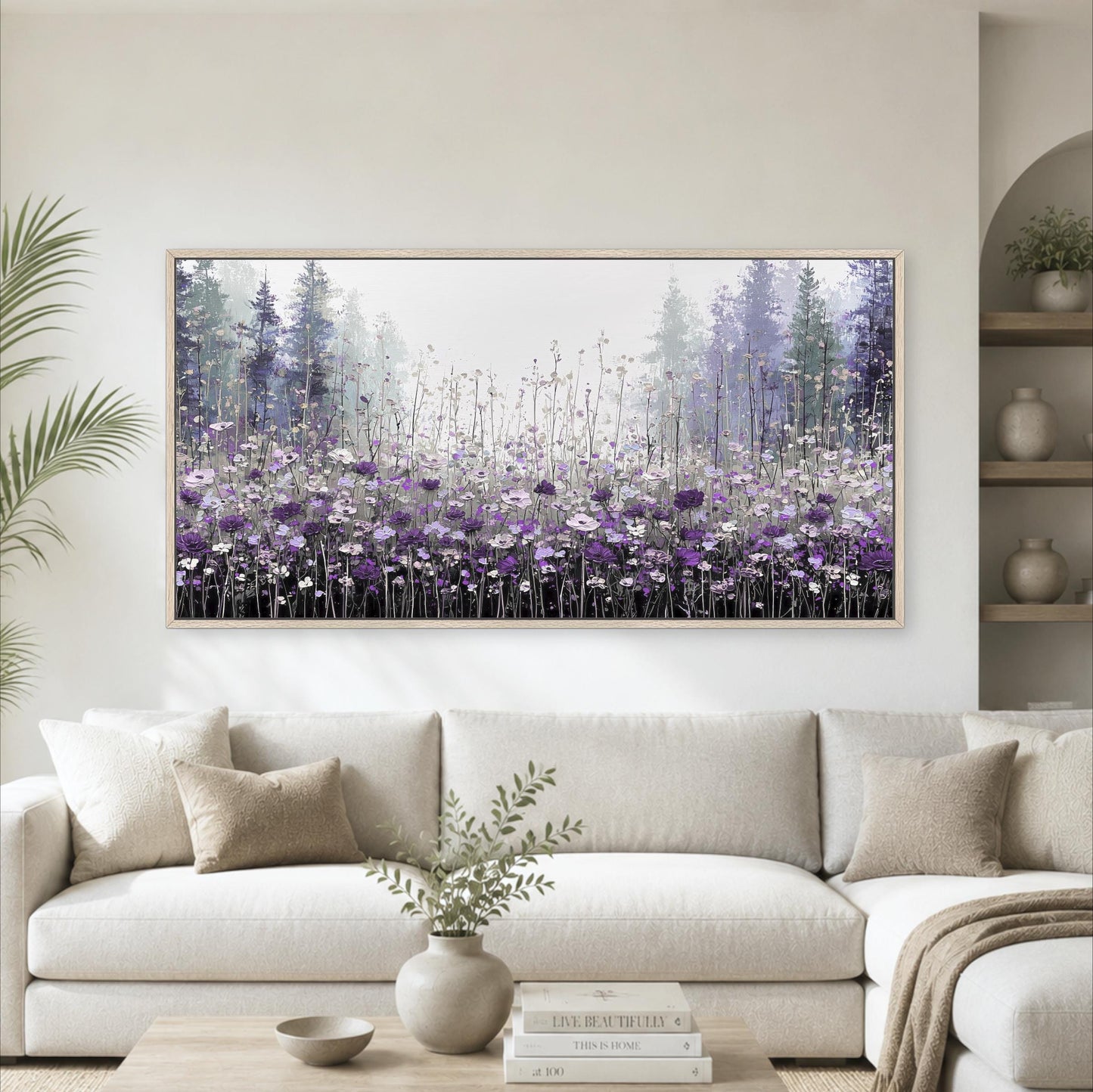 a large framed painting of a field of purple flowers hanging on a wall above a white sofa in a living room.