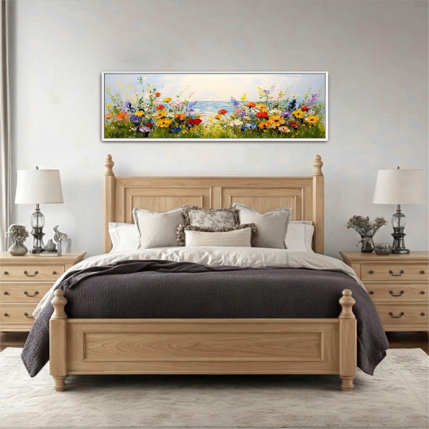 a bedroom with a large bed, wooden headboard, and nightstands with lamps. Above the bed is a framed painting depicting a field of colorful flowers.