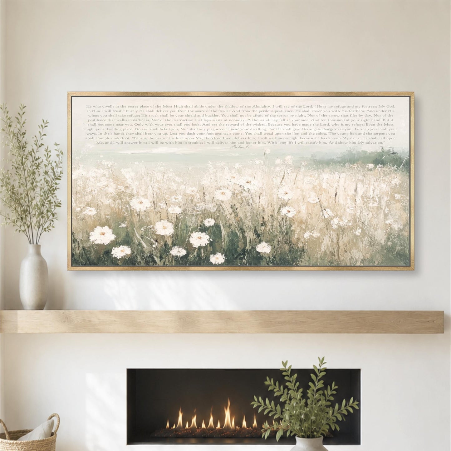 a large framed painting of a field of white flowers hanging on a wall above a fireplace. The painting is framed in gold and is placed above a wooden shelf. The fireplace has a fire burning, and there are some plants and a vase on the shelf below the painting.