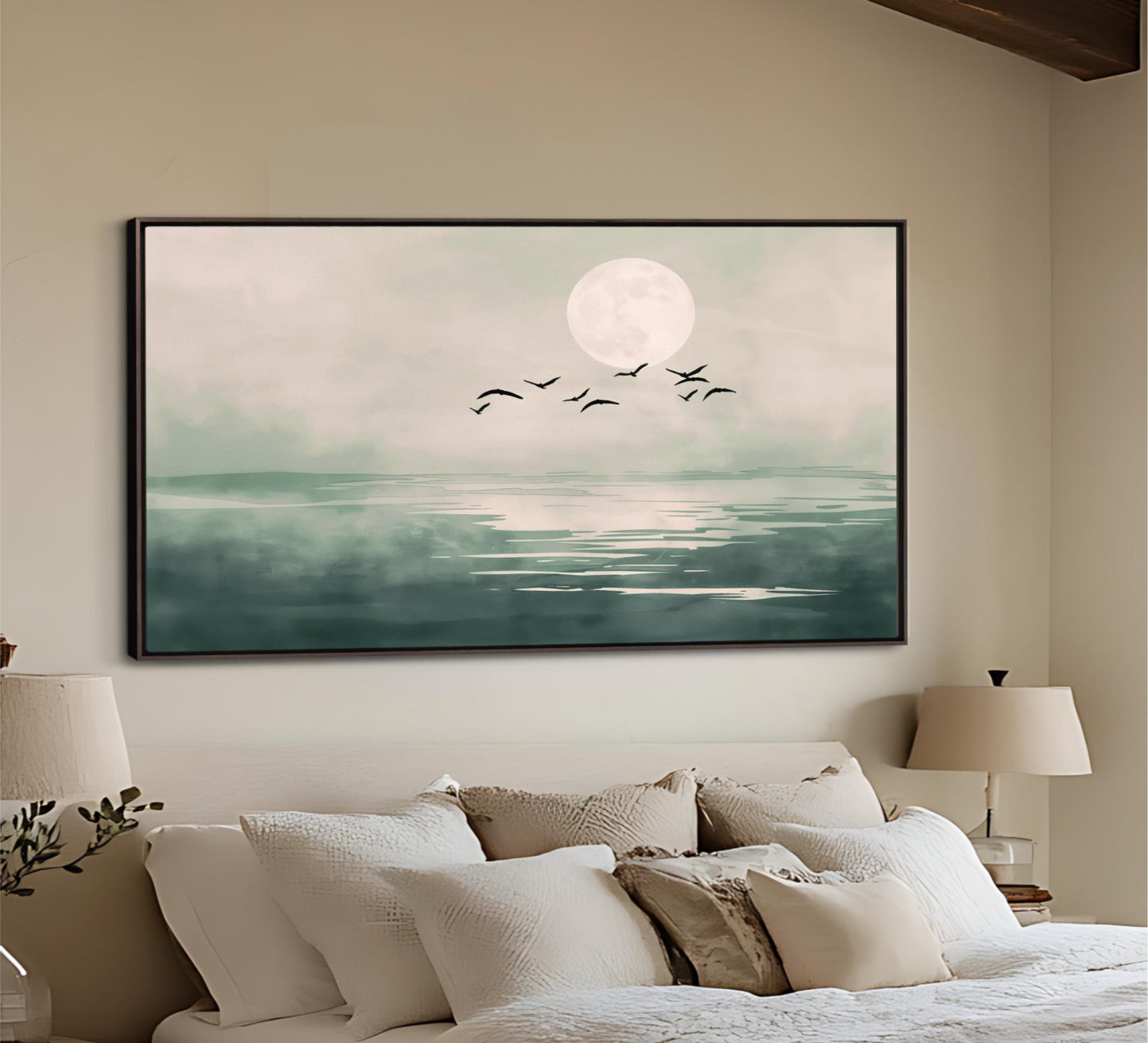 a serene bedroom scene with a large framed painting of a calm ocean and a full moon hanging on the wall above a bed with white pillows and a white headboard.
