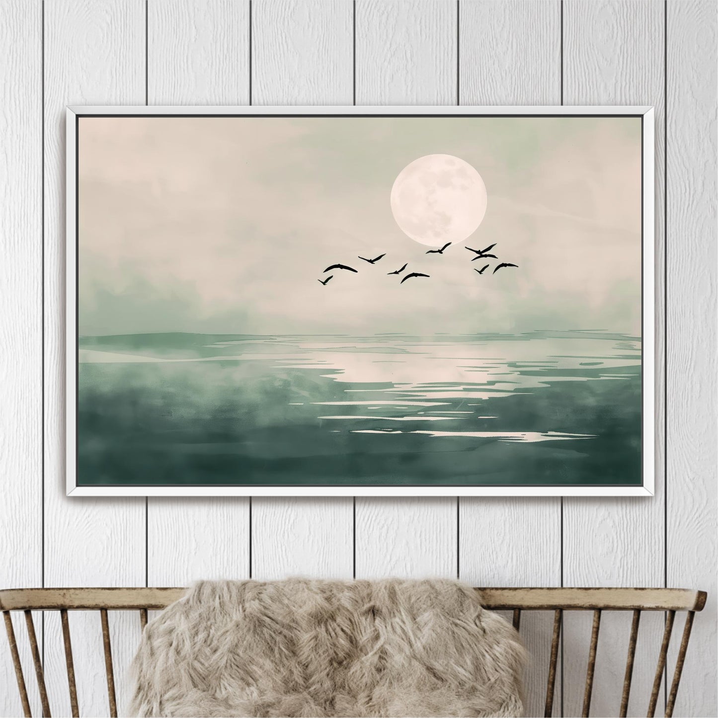 A framed painting depicting a serene landscape with a large moon, a flock of birds flying over a calm body of water.