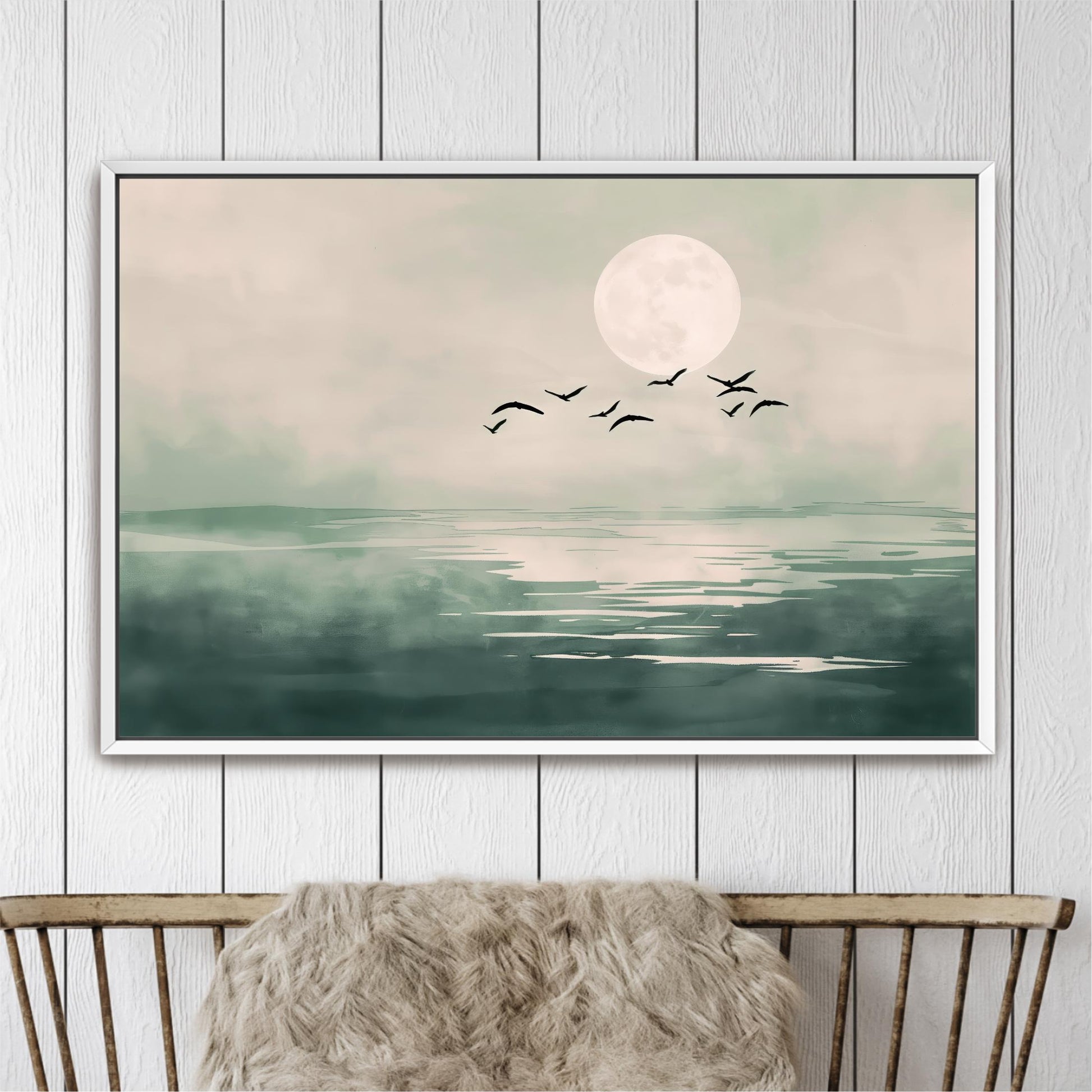 A framed painting depicting a serene landscape with a large moon, a flock of birds flying over a calm body of water.