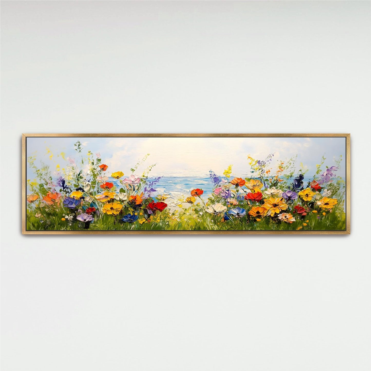 A framed painting depicting a vibrant field of colorful flowers with a body of water in the background.