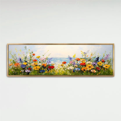 A framed painting depicting a vibrant field of colorful flowers with a body of water in the background.