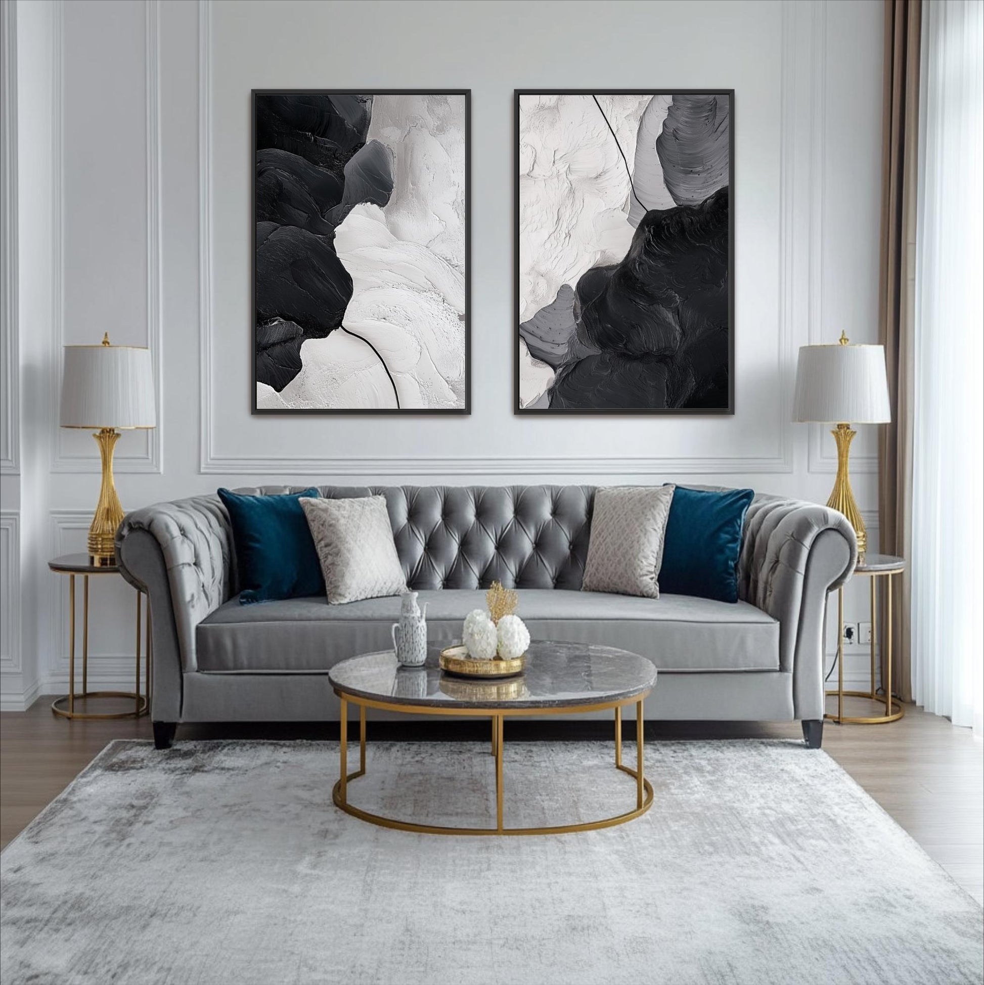 a modern living room with a gray tufted sofa, a round glass coffee table, and two gold side tables with lamps. Above the sofa, there are two abstract paintings on the wall, creating a stylish and sophisticated atmosphere.