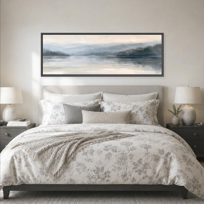 a serene bedroom scene with a large bed adorned with a floral comforter and pillows, flanked by two nightstands with lamps. Above the bed, a large framed landscape painting features a tranquil scene of a lake surrounded by mountains, creating a peaceful and calming atmosphere in the room.