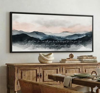 a large framed painting of a mountainous landscape with a serene and peaceful atmosphere, hanging on a wall above a wooden cabinet.