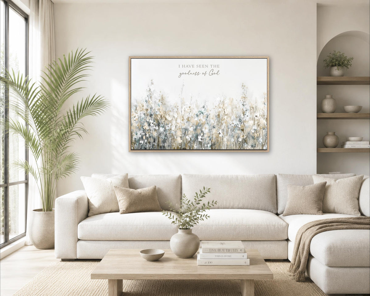 a cozy living room with a large white sofa, a wooden coffee table, and a framed artwork of a field of flowers hanging on the wall.