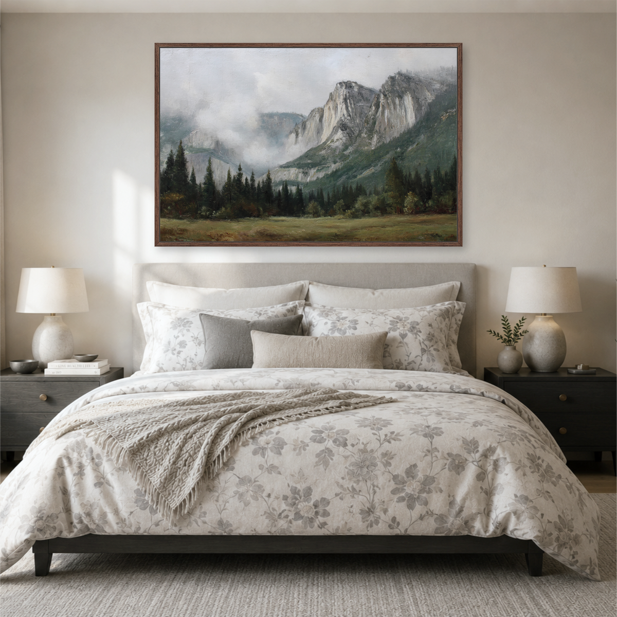 a serene bedroom scene with a large bed adorned with a floral comforter and pillows, flanked by two nightstands with lamps. Above the bed, a large painting of a mountain landscape with a misty, foggy atmosphere hangs on the wall.