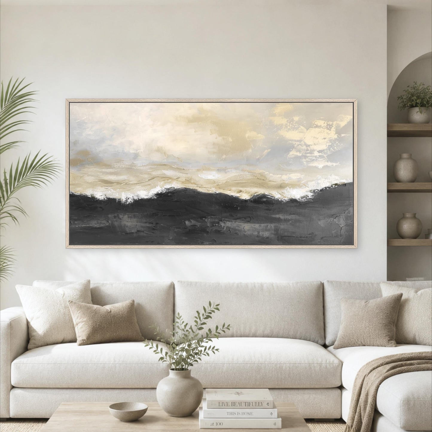 a large, framed painting of a landscape with a cloudy sky hanging on a wall above a white sofa in a living room.