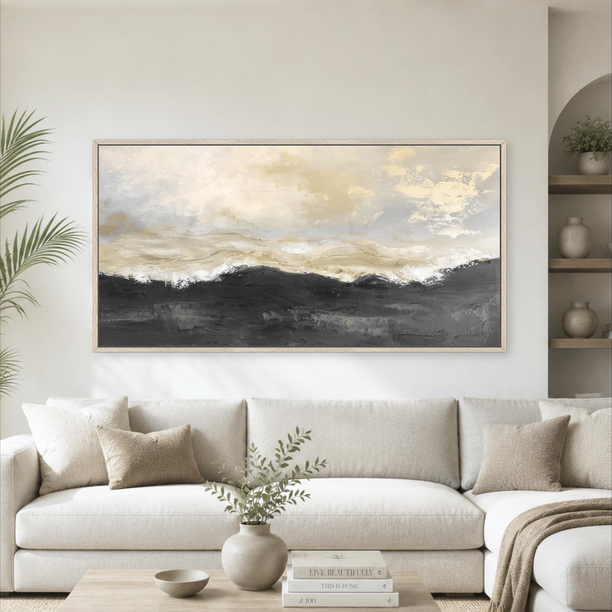a large, framed painting of a landscape with a cloudy sky hanging on a wall above a white sofa in a living room.