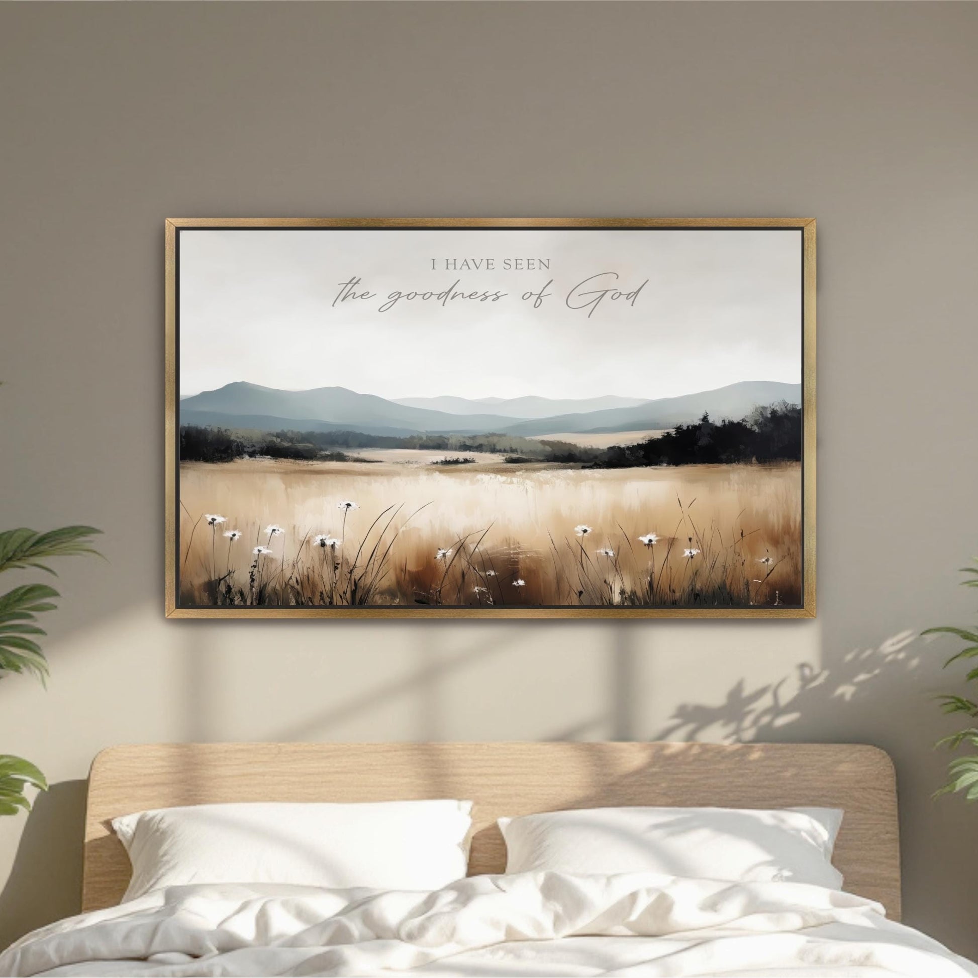 a framed landscape painting hanging on a wall above a bed with white pillows.