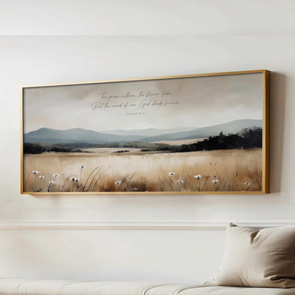 The image is a framed painting of a serene landscape with mountains, grass, and wildflowers. The painting is hung on a wall above a couch, creating a peaceful and natural atmosphere in the room.