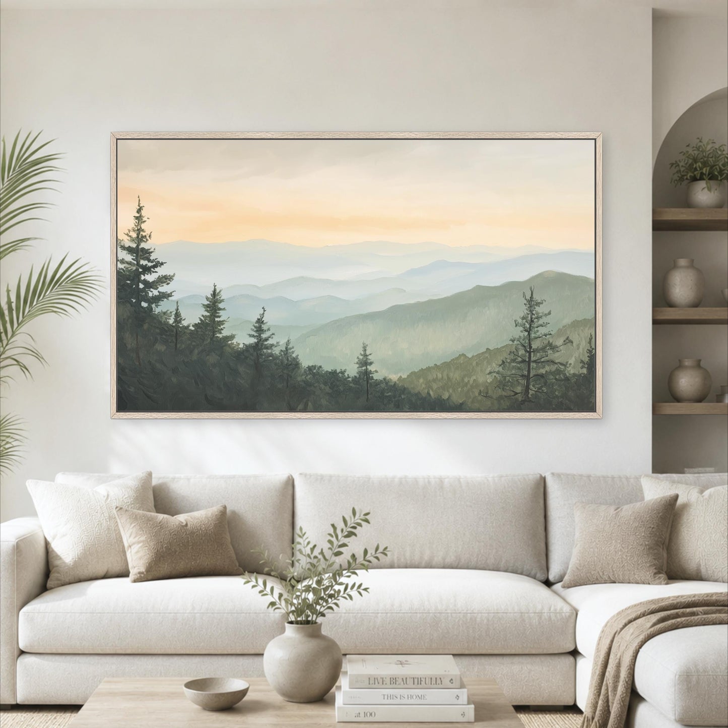 a large landscape painting hanging on a wall above a white sofa in a living room.